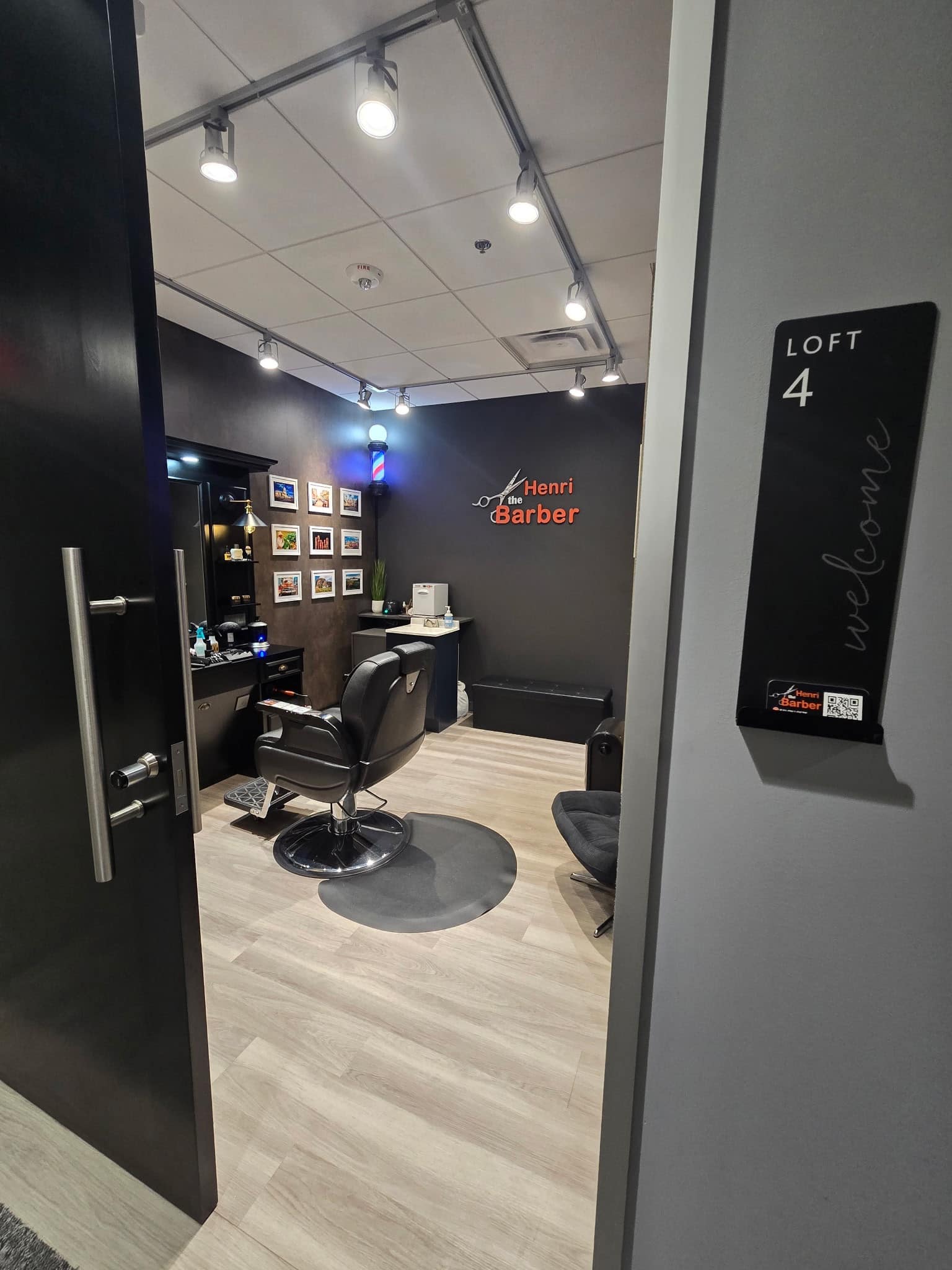 Looking into Loft 4 from the doorway: the barber chair on the mat, the station and mirror to the left, and the Henri the Barber sign on the back wall.